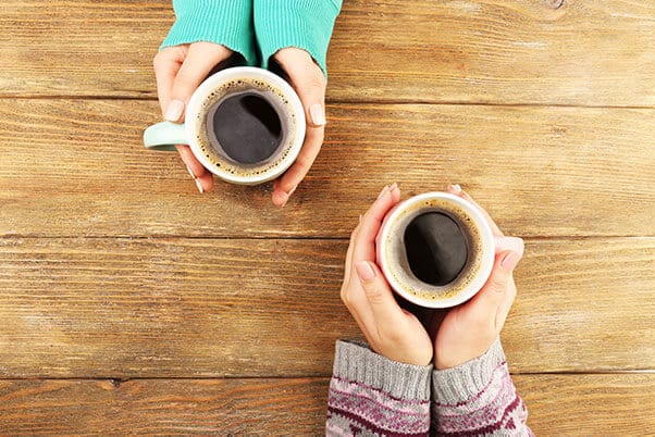 Two sets of hands holding coffee cups